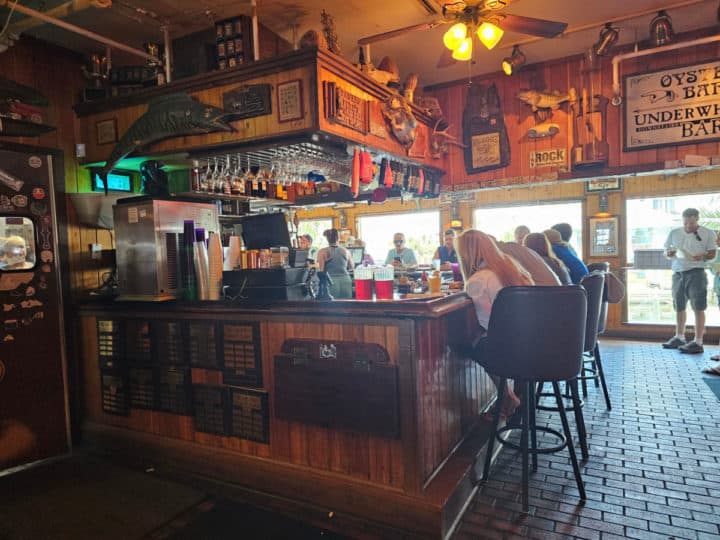 indoor bar with tall chairs, wood paneling, and tropical signs