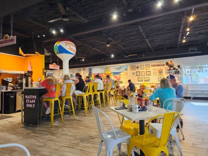 tables and chairs near a Pensacola Beach ball statue in a restaurant with art on the wall