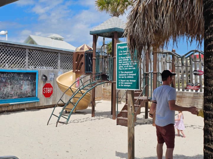 kids play structure next to a large chalkboard and palm trees