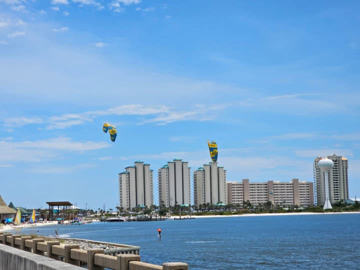 Two kite boarders in the water with hotels in the background