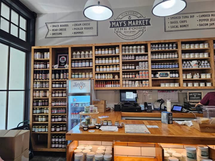 market with products on shelves behind the counter and May's Market logo on the wall