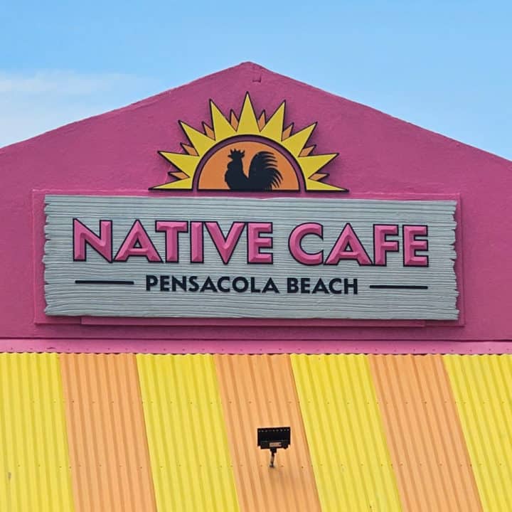 Native Cafe Pensacola Beach sign on a bright pink building with a yellow awning
