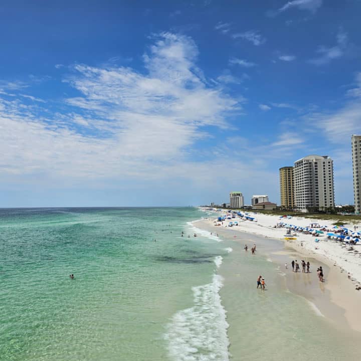 White sand beach with hotels on one side and turquoise water on the other. 