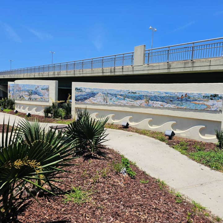 mosaic on panels with waves below and a path next to them. 