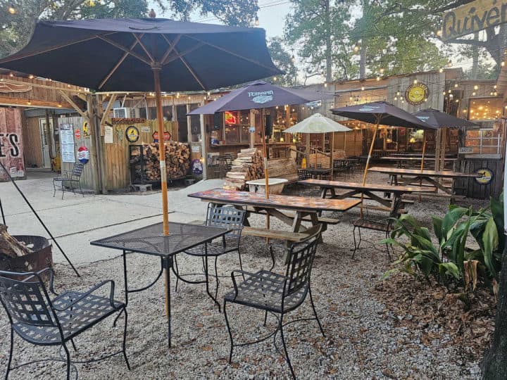 Outdoor seating with tables and chairs along with picnic tables with blue umbrellas