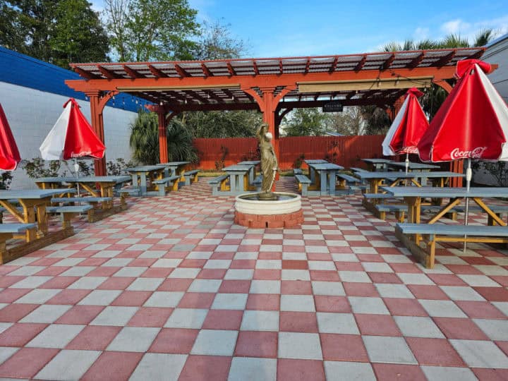 red and white checkered pattern on the ground with picnic tables that have red and whites umbrella