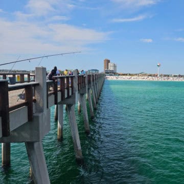 Looking down the Pensacola Beach Gulf Pier with the sand and beachball tower in the distance.