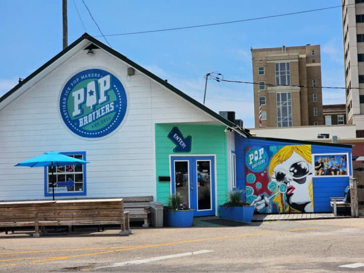 Pop brothers logo on the top of a white building next to a colorful mural