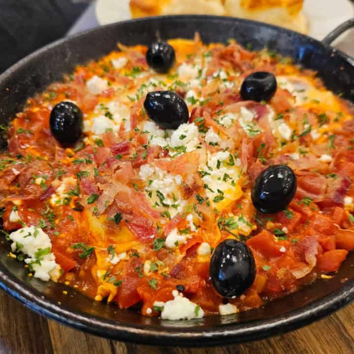 Shackshuka in a cast iron skillet topped with olives