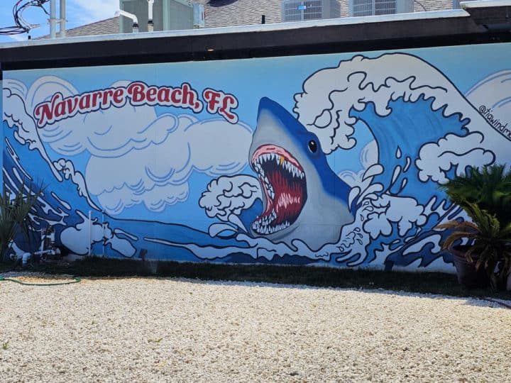 Navarre Beach shark mural with a giant wave on the side of a building