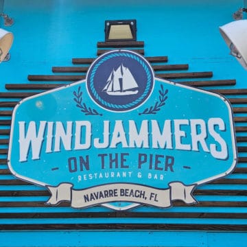Windjammers on the Pier, Navarre Beach, FL sign with a sailboat and two lights next to it