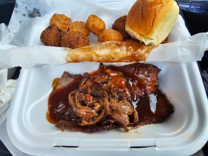 brisket, bread, and hushpuppies in a Styrofoam container 