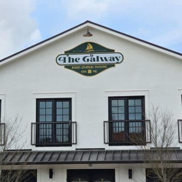 The Galway Irish Public House sign on a white building above two windows and an awning