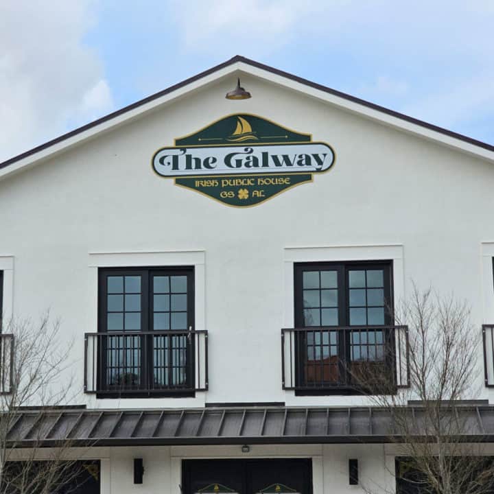 The Galway Irish Public House sign on a white building above two windows and an awning