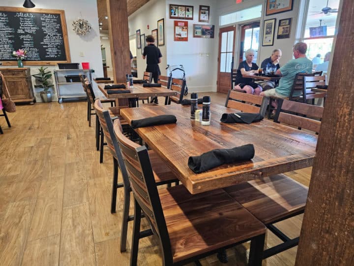 Tables and chairs with napkins on the tables. People eating at tables in the background. 