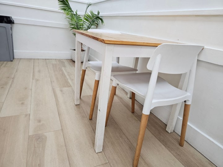 White tables and chairs with wooden legs next to a plant in Del's Ice Cream Shop