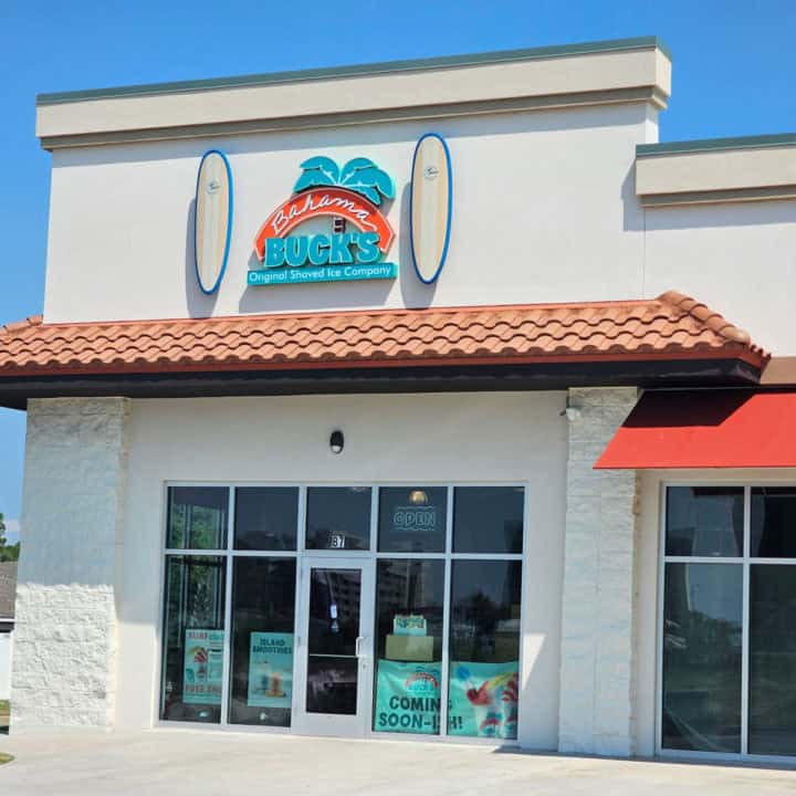 Bahama Bucks Original Shaved Ice sign between two surfboards over restaurant entrance with coming soon signs 