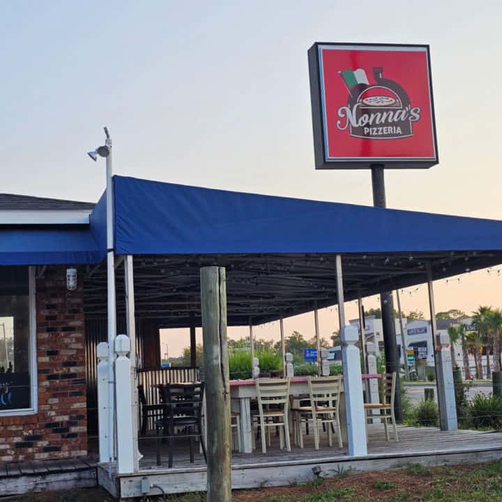 Nonna's Pizzeria sign over a blue awning with outside seating. 