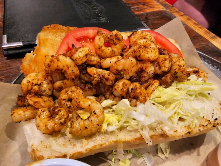 Shrimp po boy with lettuce and tomato on a po boy bun