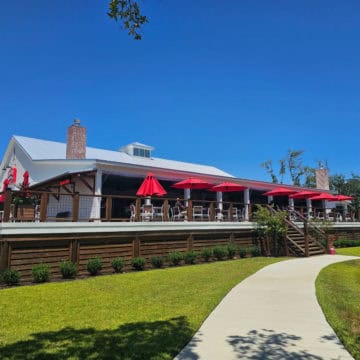 Tin Top restaurant exterior with large deck, tables and chairs with red umbrellas