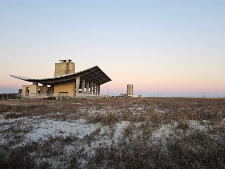 Beach pavillion near dunes with pink skies in the background