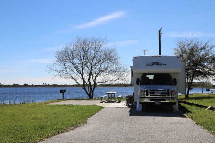 RV backed into a campsite with the lake behind it. 