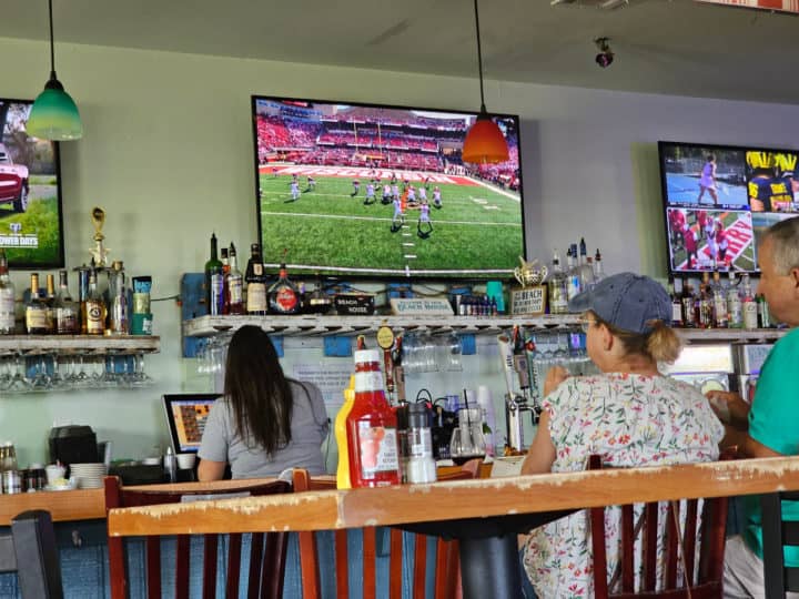 Football games on tv's above the bar with people sitting at the bar