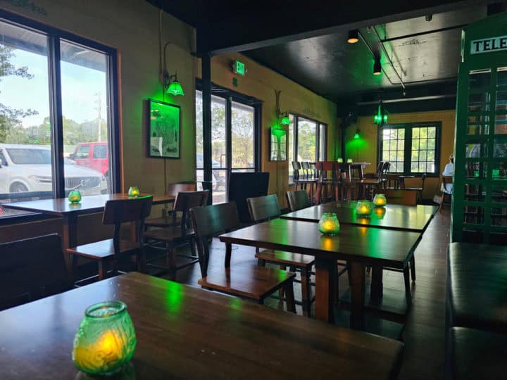 Indoor tables and chairs near an Irish phone booth, green lights hanging from the ceiling. 