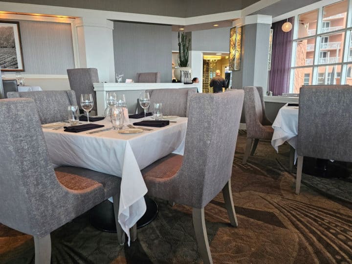 grey chairs next to a white linen covered table with wine glases