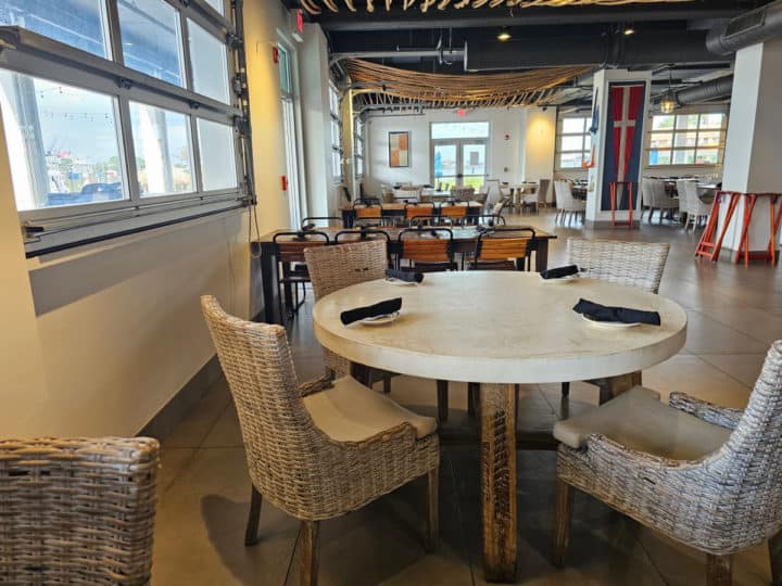 inside Zeke's restaurant with white circle tables and chairs, near larger tables with wooden chairs. nautical art on the wall