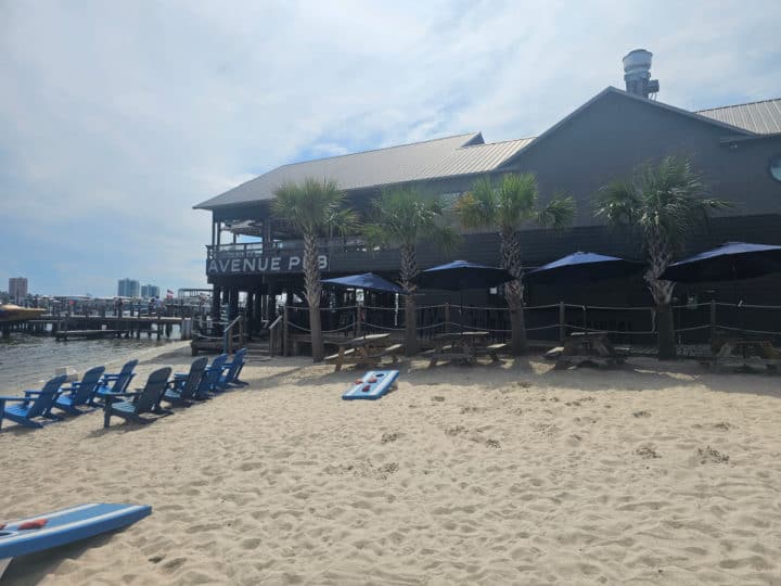 Avenue pub building in the background with sand and Adirondack chairs below it. 