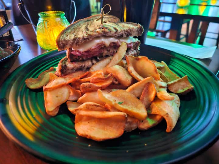 Reuben sandwich on a green plate with fries