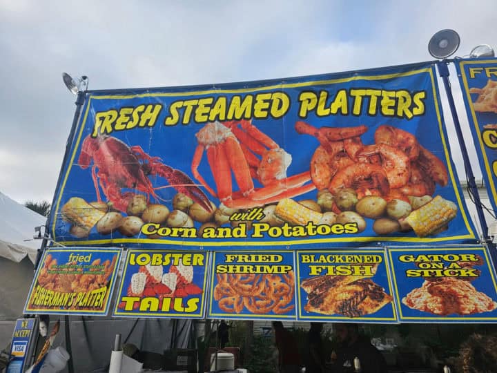 Fresh steamed platters with crab, seafood, and gator on a sign