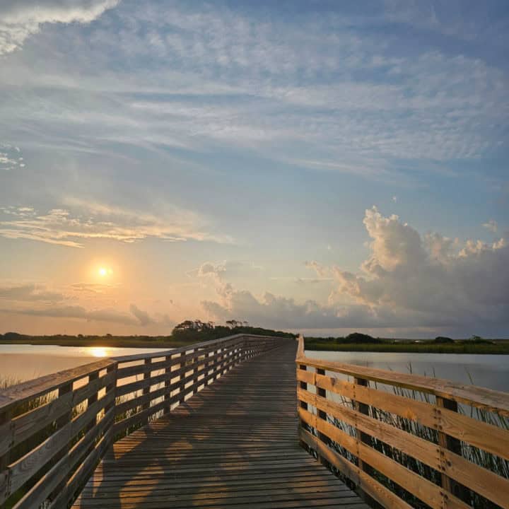 Boardwalk over Lake Shelby in Gulf State Park with sunrise over the water 