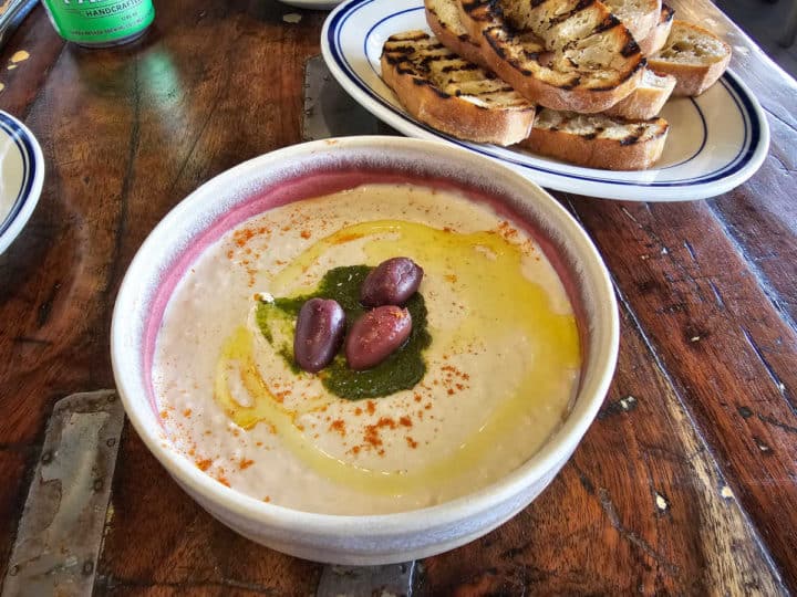 White bean hummus in a bowl next to a plate of toasted sourdough bread slices