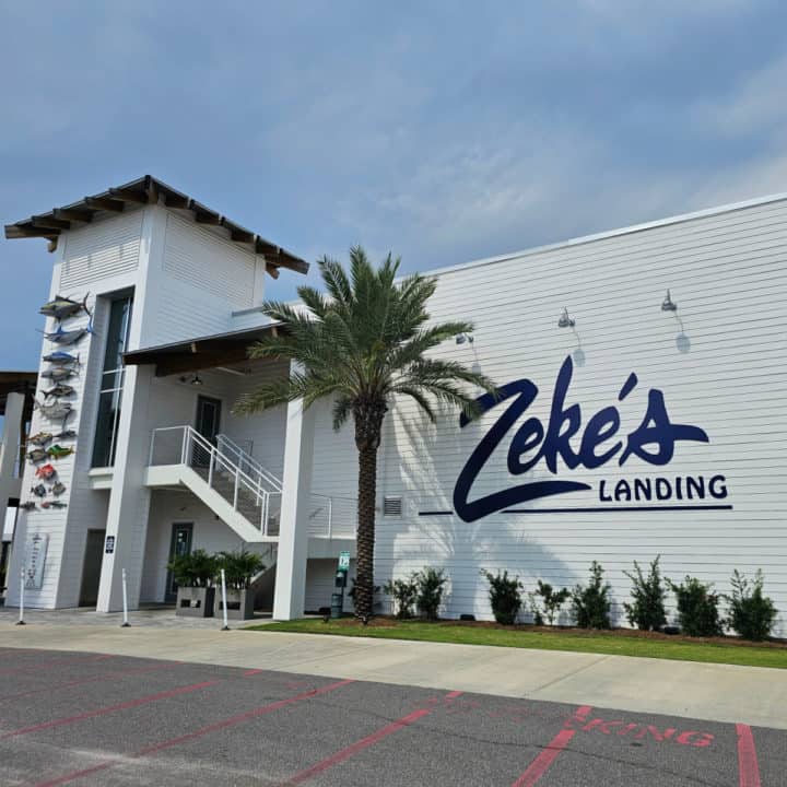 Large White building with Zeke's Landing in blue letters across the side of it. Fish art down one side of the wall