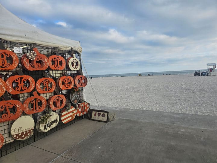 pumpkin art on the side of a tent next to the beach with the Gulf in the background