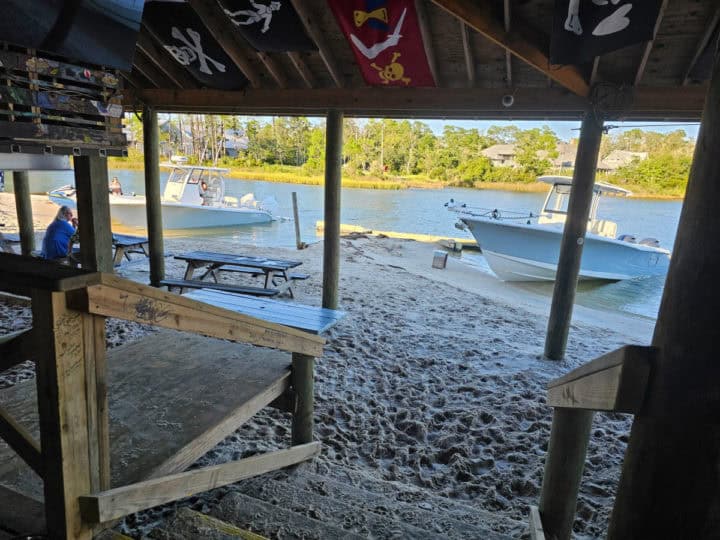 boats pulled up to the sand seen from under the Pirates Cove outdoor awning