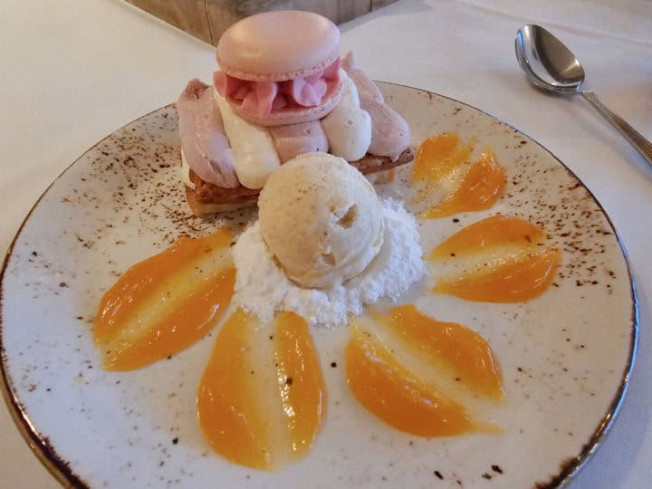 raspberry macaron on a pastry next to banana ice cream with passion fruit gelee on the plate