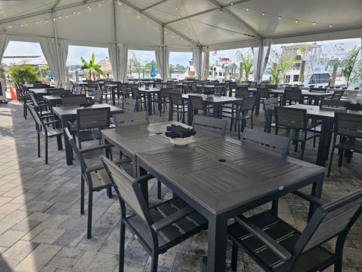 Outdoor tables and chairs in rows under a large white tent