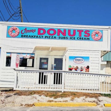 Amore donuts sign above a white building with glass door entrance