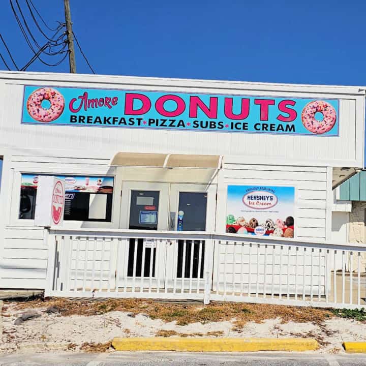 Amore donuts sign above a white building with glass door entrance