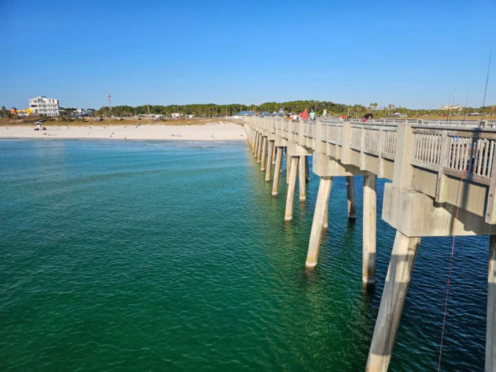 looking down the MB Miller Pier towards the beach with fishing lines over the side of the pier. 