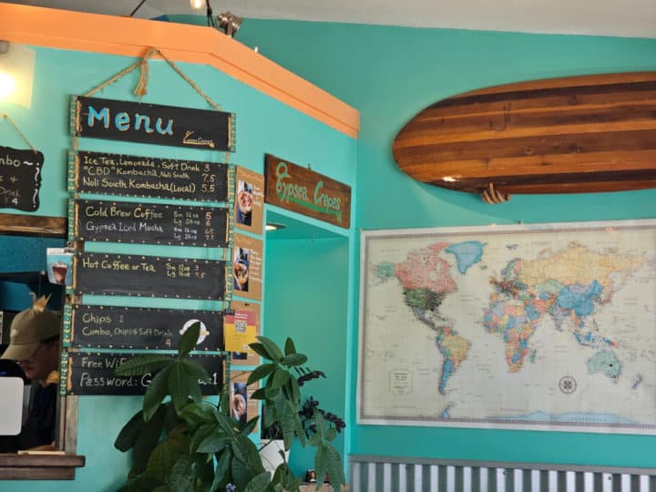 drink menu on chalkboard next to a world map and surfboard