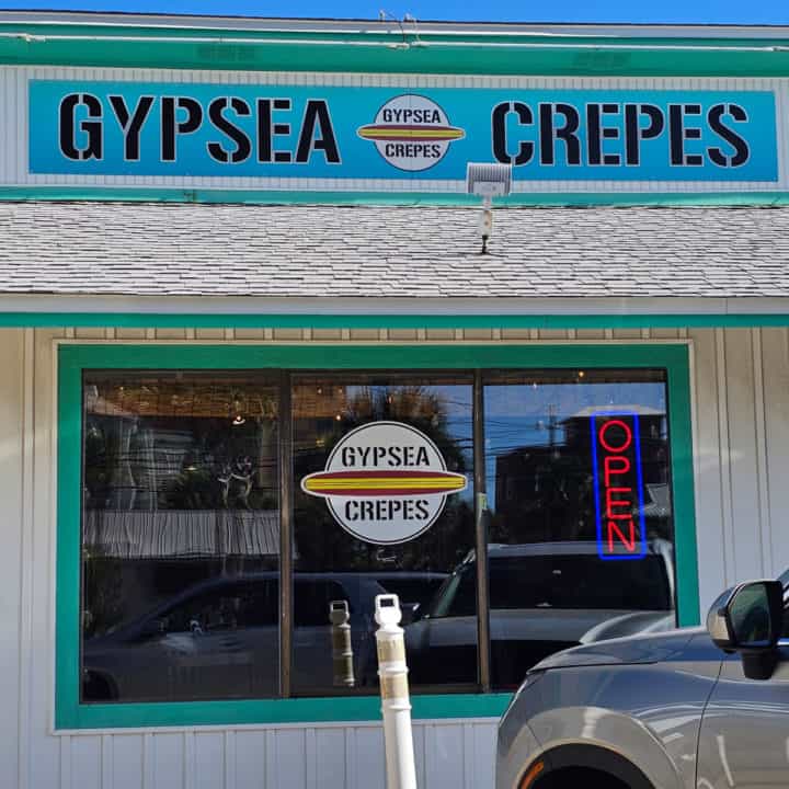 Gypsea Crepes blue sign over a glass window with Gypsea Crepes logo and open sign