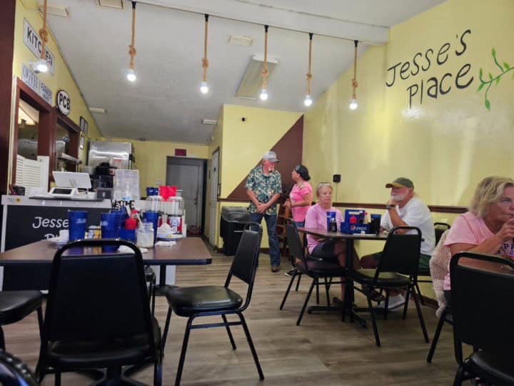 indoor seating with table and chairs below a mural with Jesse's Place on a yellow painted wall. 