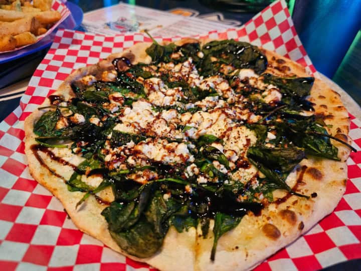 Thin crust pizza with spinach and goat cheese drizzled with balsamic glaze