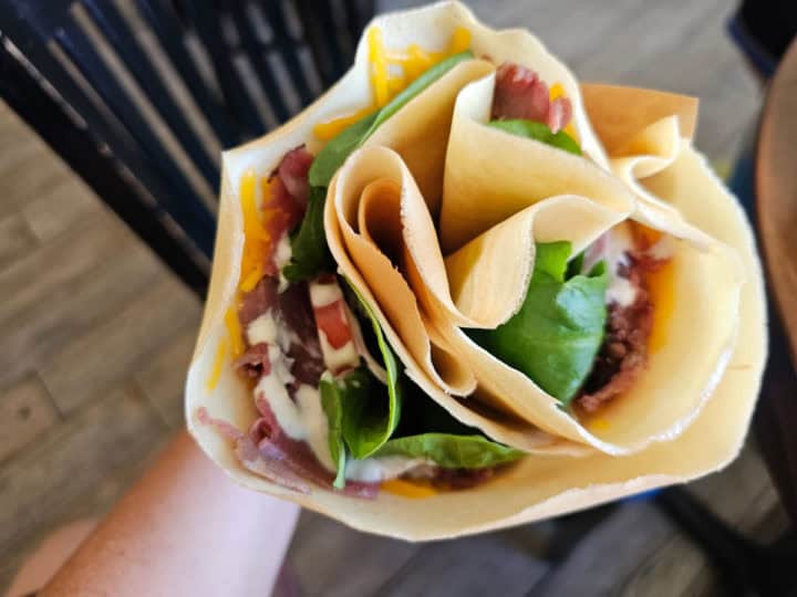 crepe with roast beef spinach, and tomatoes being held