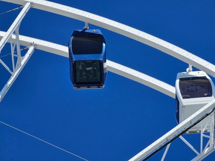 Blue gondola with clear floor on the Panama City Beach SkyWheel next to a white gondola