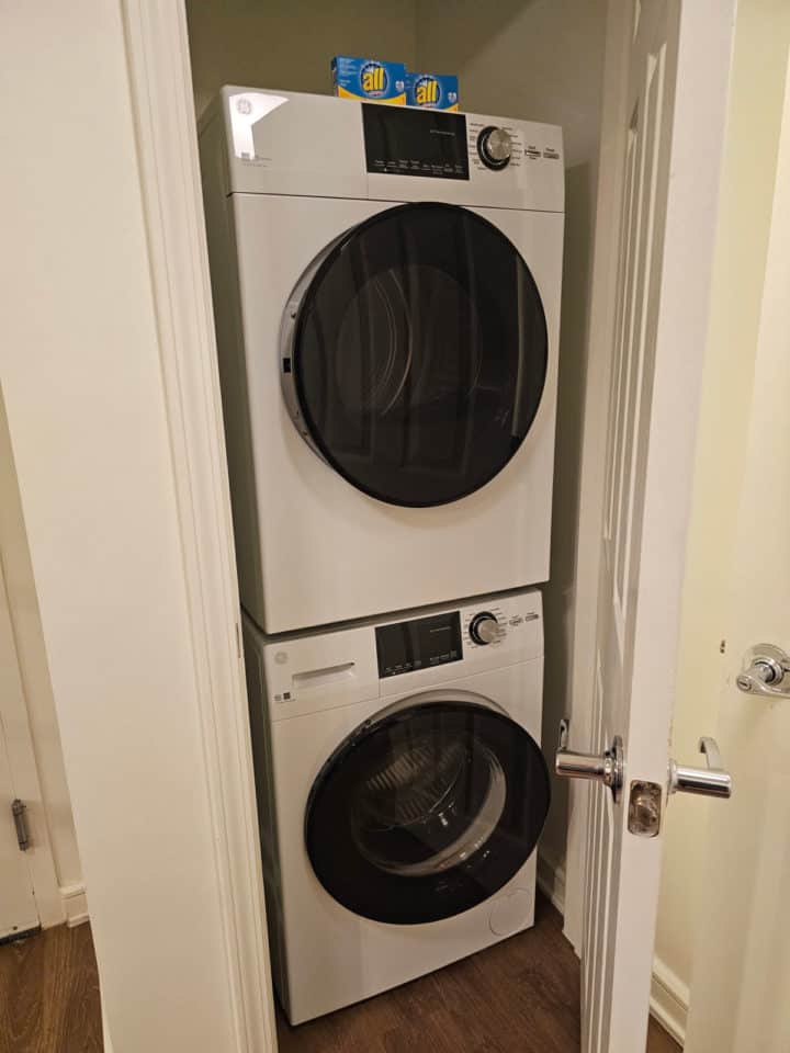 washer and dryer stacked in a closet with two boxes of ALL detergent on top